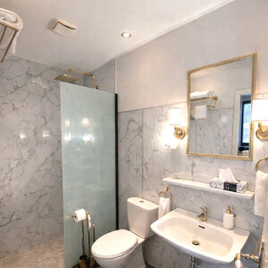 Modernes Badezimmer im Landhotel Römerkessel mit ebenerdiger Glasdusche, WC und Waschbecken, hell gefliest und sauber ausgestattet im Hotelzimmer.